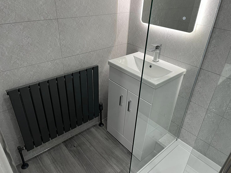 Grey bathroom with dark grey radiator and LED mirror